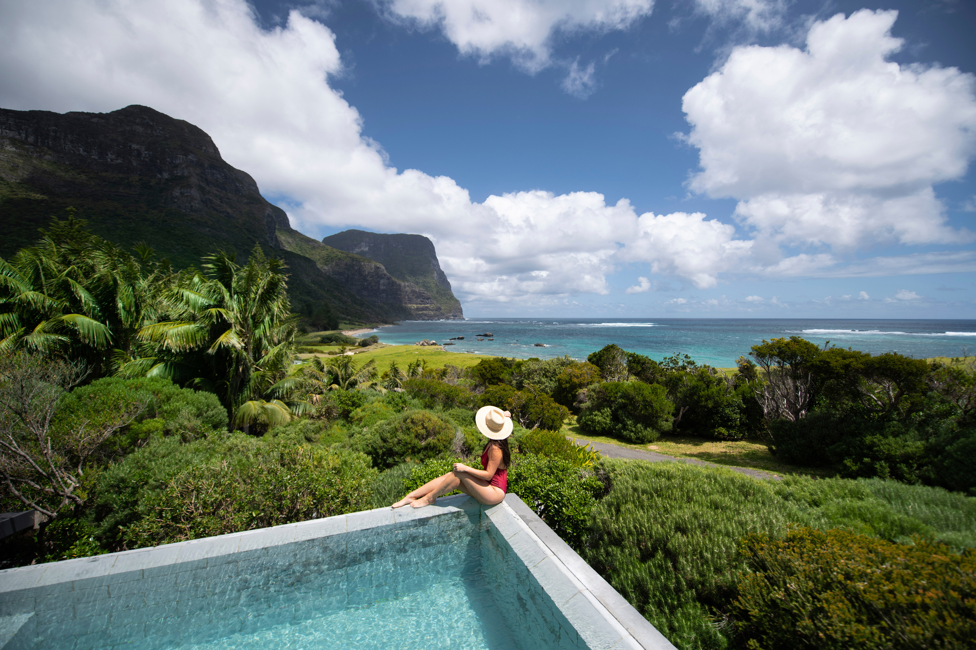 Woman relaxing by the pool at Capella Lodge, Lord Howe Island. 